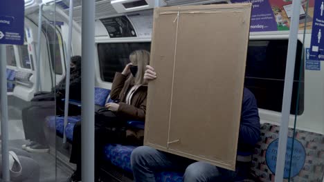 View-Of-Male-Holding-Large-Art-Frame-Canvas-On-Jubilee-Train-In-London---17-March-2022