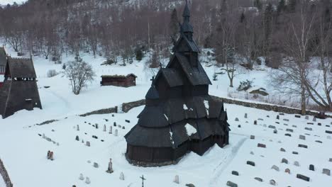Orbit-around-Borgund-stave-curch-from-viking-era-in-Norway---Winter-aerial-with-church-in-center-and-snowy-landscape