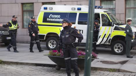 Policewoman-standing-on-Karl-Johan,-Oslo-during-military-parade-with-policecar-behind