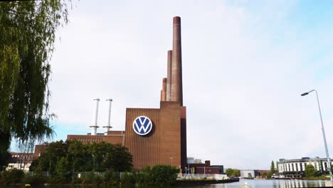 View-Looking-At-VW-Logo-On-Side-Of-Volkswagen-factory-Building-With-Chimney-Towers-At-Wolfsburg,-Germany
