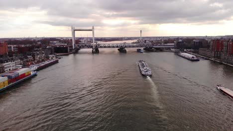 Aerial-Over-Oude-Maas-With-Ships-Making-Approach-To-Spoorbrug-Railway-Bridge-Against-Sunset-Skies-In-Dordrecht