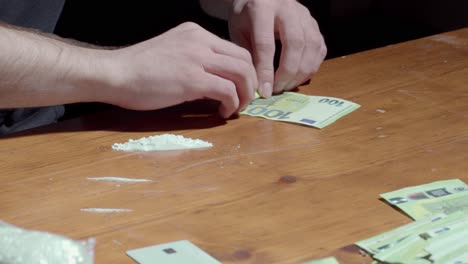 Drogenabhängiger-Rollt-100-Euro-Banknote-Auf-Den-Tisch-Und-Schnaubt-Kokainpulver