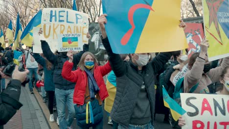 Ukrainer,-Die-Gegen-Die-Russische-Invasion-Protestieren,-Gehen-Zusammen-Mit-Koreanern-Und-Halten-Plakate-In-Der-Hand