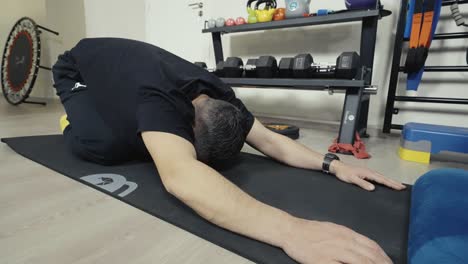 overweight-man-exercising,-doing-stretching-exercises-on-yoga-mat-at-home