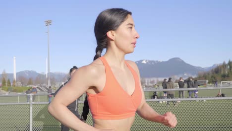 Tracking-alongside-young-athletic-woman-running-on-track-Medium-Shot