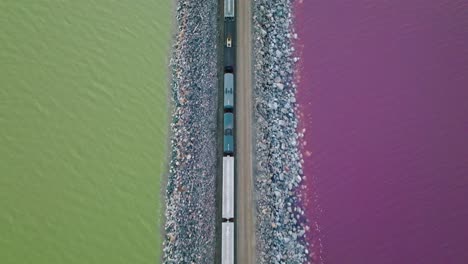 AERIAL---Railway,-purple,-green-water-in-Lucin-Cutoff,-Great-Salt-Lake,-Utah,-top-down