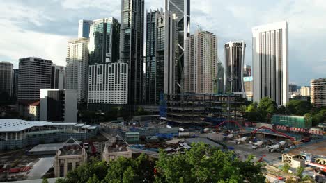 aerial-drone-overlooking-an-industrial-construction-zone-in-downtown-Kuala-Lumpur-Malaysia-on-a-sunny-day-as-the-sun-begins-to-set-overlooking-the-grand-skyline-and-many-skyscrapers