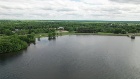 Aerial-panoramic-view-of-the-lake-and-forest-landscape-on-the-side-of-a-road