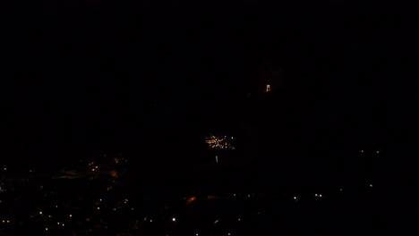 Celebration-with-many-little-and-colorful-fireworks,-over-a-mountain-town,-at-night
