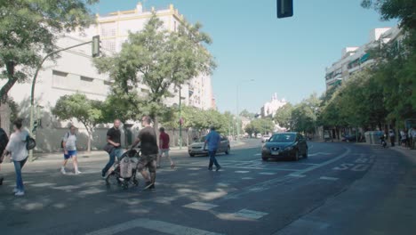 People-crossing-crosswalk-at-major-avenue-in-Seville,-Spain