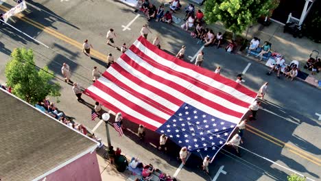 Tilt-down-pan-aerial-shot-of-Boy-Scouts-of-America-carrying-start-spangled-banner-American-flag-in-small-town-parade