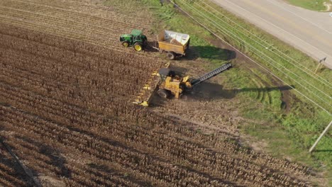 Aerial-view-rotating-counter-clockwise-from-the-side,-harvester-starting-a-new-row-of-seed-corn-next-to-a-road-for-next-years-planting