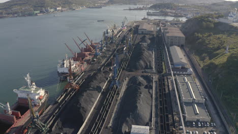 Coal-loading-cargo-operations-at-the-coal-terminal,-with-moored-general-cargo-ships,-cranes-and-port-machinery-in-operation-in-the-afternoon