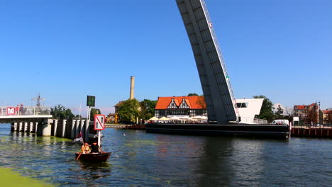 Tourist-entertainment,-a-small-boat-with-a-pirate-flag-and-two-pirates-crossing-under-the-Drawbridge,-Motlawa-river,-Gdansk,-poland