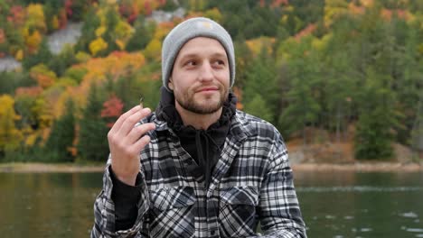 Handsome-young-man-smiles-and-smokes-a-weed-joint-in-autumn,-handheld