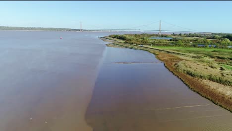 Tolle-Aufnahmen-Eines-Drohnenflugs-In-Geringer-Höhe-über-Dem-Wattenmeer-Des-Flusses-Humber-Im-Vereinigten-Königreich,-Der-Auf-Die-Berühmte-Humber-Brücke-Zufliegt