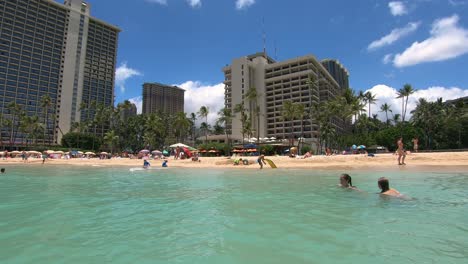 Langsamer-Schwenk-Vom-Strandmeer-Und-Hotels-Im-Hintergrund-Am-Strand-Von-Waikiki,-Honolulu,-Hawaii