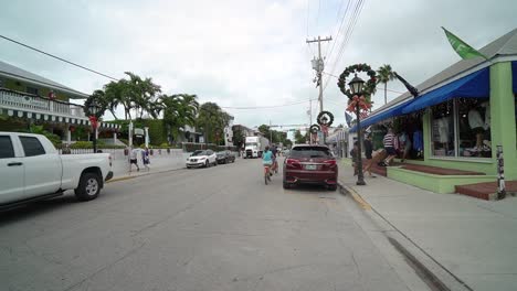 Key-West-Street-With-Streep-Lamps-Decorated-With-Christmas-Wreaths-With-Couple-Riding-Beach-Cruisers-Down-Street