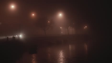 Light-beams-cast-by-car-driving-through-dense-fog-by-river