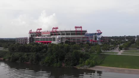 View-from-river-of-Nashville-Illinois-stadium-exterior-facade-and-green-landscape,-rising-forward-aerial