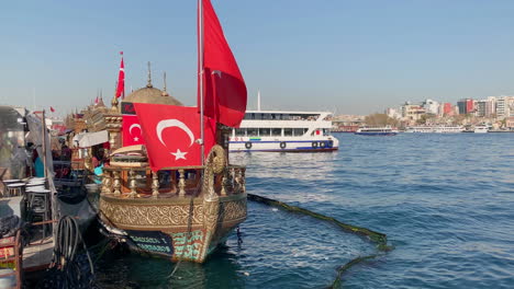 Vintage-boat-with-Turkish-national-flags-floating-on-water-on-Eminönü-ferry-terminal-in-Istanbul