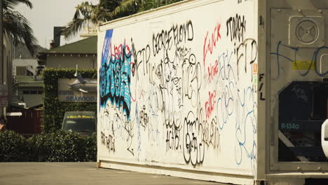 BLM-graffiti-on-container-in-Los-Angeles-with-protestors-walking-passed