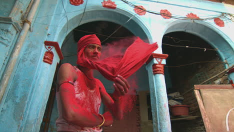 Man-covered-in-red-powder-removes-a-cloth-from-his-face