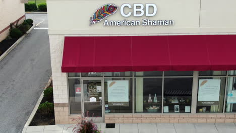 CBD-legalized-medical-marijuana-to-buy-sell-for-medicinal-purposes,-aerial-of-storefront-entrance,-American-Shaman,-legalization-of-drugs-in-America-USA