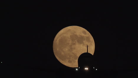 An-airliner-passes-in-front-of-a-full-moon-on-approach-to-landing-at-Los-Angeles-International-Airport-in-slow-motion