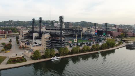 Aerial-approach-toward-PNC-Park,-home-of-Pittsburgh-Pirates,-boat-in-Allegheny-River,-baseball-diamond-and-turf-grass-field-visible