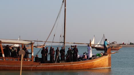 A-view-of-traditional-wooden-boat-known-as-Dhow,-carrying-a-group-of-local-people-singing-and-dancing-at-Katara-Village,-Doha,-Qatar-on-the-occasion-of-Dhow-Festival