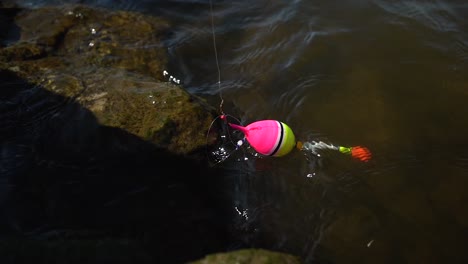 Fishing-float-bob-equipment-in-river-water-on-fishing-line,-ready-for-catch