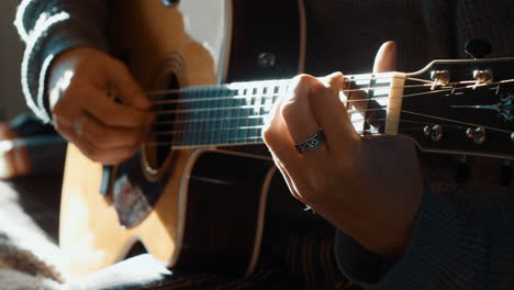Man-with-rings-playing-acoustic-guitar-with-beautiful-sunlight-on-it