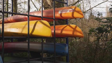 Canoes-stored-stacked-organized-behind-on-a-metal-rack-during-autumn-fall-off-season-in-public-park-facility-deer-lake