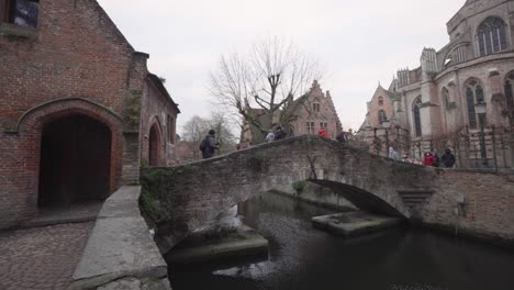 People-Cross-At-Bonifacius-Bridge-Near-Church-Of-Our-Lady-In-Bruges,-Belgium-During-Pandemic