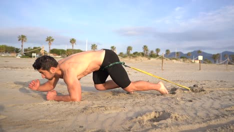 endurance-activity-dragging-a-kettlebell-attached-to-a-rubber-band-crawling-on-the-sand