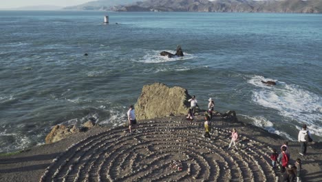 Tilt-Shot-of-People-Walking-Around-the-Land's-End-Labyrinth-Art-Maze-Near-the-Crashing-Waves-of-the-Pacific-Coast