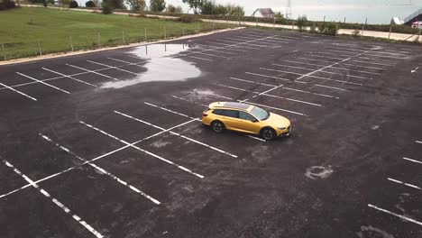 Aerial-view-of-a-yellow-Opel-Insignia-car-parked-on-a-raw-asphalt-parking-lot