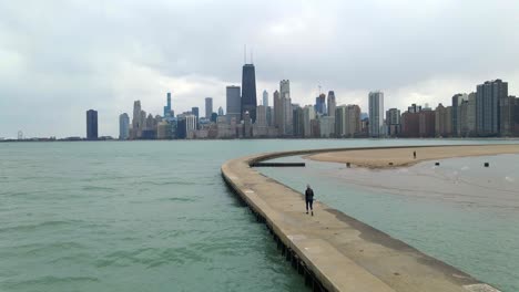 person-walking-in-lake-michigan,-chicago-downtown-seen-in-the-background,-travel-and-visit-illinois