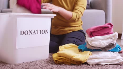 Closu-up-of-woman-selecting-clothes-for-donation-and-putting-them-in-a-box