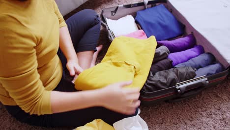 Young-woman-preparation-suitcase-getting-ready-for-road-trip-preparing-luggage-for-vacation