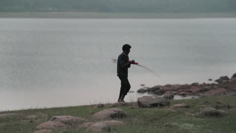 Poor-Indian-fisherman-walking-away-from-the-lake,-Side-angle-shot