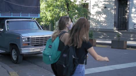 Young-adults-wearing-masks-walking-across-the-street-as-an-old-truck-waits-at-the-light