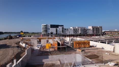 Slow-forward-aerial-movement-showing-construction-site-of-luxury-apartment-Kade-Zuid-complex-being-build-in-former-industrial-area-with-finished-Kade-Noord-behind-recreational-port-in-the-background