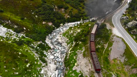 Aerial:-steam-train-running-along-a-winding-road-and-along-the-Rhone-river