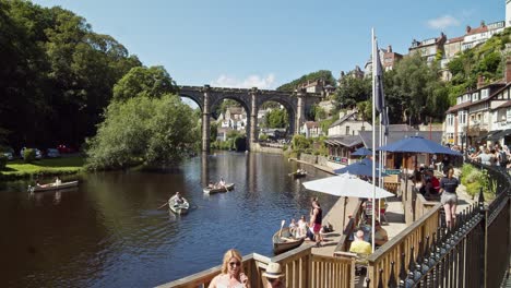 Knaresborough-Yorkshire-England-UK,-people-relaxing-in-cafe-bars-at-side-of-river-Nidd-watching-people-in-rowing-boats