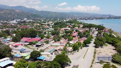 Aerial-drone-of-capital-city-Dili-in-remote-tropical-island-Timor-Leste,-South-East-Asia,-lowering-towards-road-and-traffic
