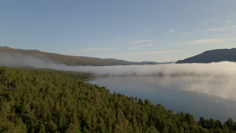 Aerial-flight-over-foggy-alpine-landscape-and-calm-lake
