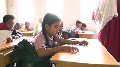 Young-School-Girl-Reading-At-Desk-In-Classroom-In-Pakistan