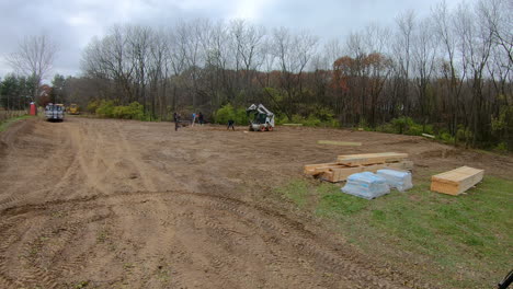 Time-lapse-of-small-construction-crew-using-a-skid-steer-loader-to-dig-holes-for-the-principal-framing-poles-for-new-construction-of-a-pole-barn